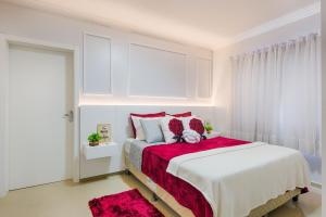 een witte slaapkamer met een groot bed met rode kussens bij APT MODERNO À 60 METROS DO TERMAS in Piratuba