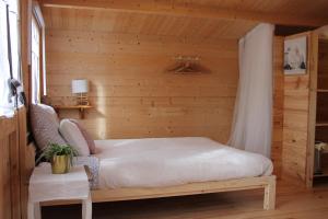 una camera con un letto su una parete in legno di Chambre élégante dans chalet SDB partagée à proximité a Chavagne