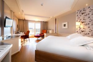 a hotel room with a white bed and a desk at La Clairière bio & spahotel in La Petite-Pierre