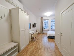 a white bedroom with a bed and a desk and a window at Kyiv Honchara Hotel in Kyiv