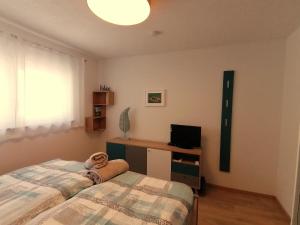 a bedroom with two beds and a desk with a television at Ferienwohnung Am Wolfsweg in Merzig