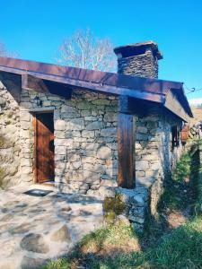 un edificio in pietra con una porta in legno e un tetto di Casa da Covinha - Branda da Aveleira a Melgaço