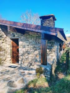 a stone building with a wooden door and a roof at Casa da Covinha - Branda da Aveleira in Melgaço