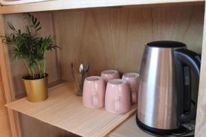 a shelf with pink cups and a pot on it at Chambre élégante dans chalet SDB partagée à proximité in Chavagne