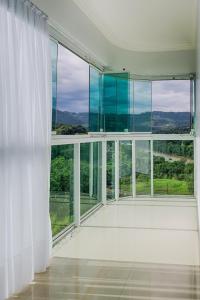 een lege kamer met grote ramen en witte gordijnen bij APT MODERNO À 60 METROS DO TERMAS in Piratuba