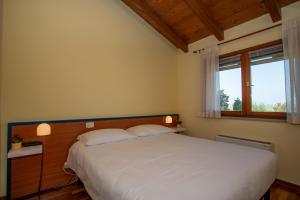 a bedroom with a white bed with a window at Hotel Caneo in Fossalòn