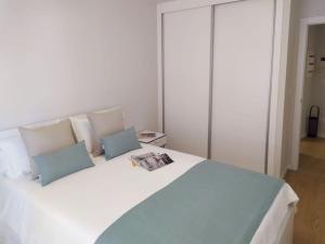 ein weißes Bett mit zwei Kissen und eine Zeitschrift darauf in der Unterkunft 0143 Apartamento nuevo y céntrico in Vigo