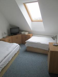 sypialnia na poddaszu z 2 łóżkami i telewizorem w obiekcie Hotel Rustikal w mieście Hustopeče