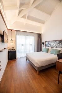 1 dormitorio con 1 cama grande y suelo de madera en Latitude 21, en Saint-Gilles-les-Bains