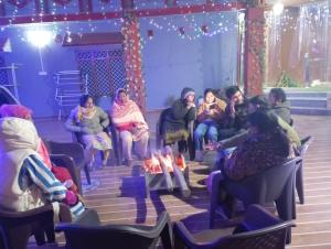a group of people sitting in chairs in a room at Mehra Cottage in Almora