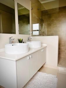 een badkamer met 2 wastafels en een spiegel bij No Load-Shedding Holiday Home in Mataffin