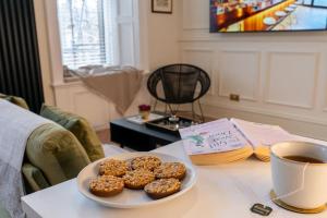 a table with a plate of donuts and a cup of coffee at The Devonshire Suite - Your 5 STAR West End Stay! in Glasgow