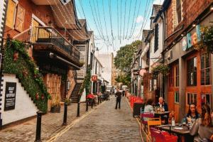 a cobblestone street with people sitting at tables in an alley at The Devonshire Suite - Your 5 STAR West End Stay! in Glasgow