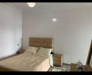 een slaapkamer met een bed en een witte muur bij Residence miramar in Mohammedia