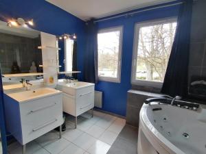 a blue bathroom with two sinks and a bath tub at L'Odyssée VILLA ILOA in Dommartemont