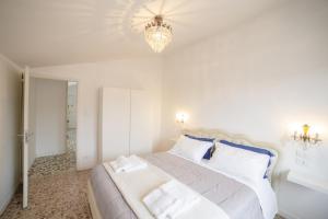 biała sypialnia z dużym łóżkiem z niebieskimi poduszkami w obiekcie Ca Rosalba by Venicevillas w Wenecji