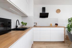 cocina con armarios blancos y microondas negro en Osiedle Latarników Apartment Gdańsk by Renters en Gdansk