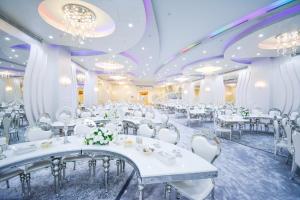 a banquet hall with white tables and white chairs at Reef Global Hotel in Makkah