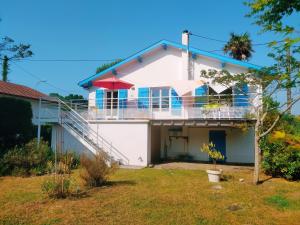 uma casa branca com janelas azuis e uma varanda em Villa Dziunia Jardin Terrasse ok em Tarnos