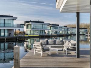 a living room with a couch and chairs on a dock at Luxury villa with boathouse on the Veerse Meer in Arnemuiden