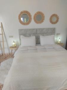 um quarto com uma cama grande e dois espelhos na parede em Petit paradis em Sidi Bibi