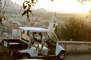 a golf cart parked on a wall with a view of a city at Albergo Diffuso Mannois in Orosei