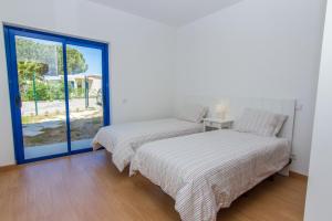 two beds in a room with a window at Apartamentos Clube da Bemposta in Alvor