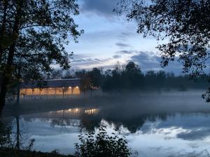a misty lake with a building in the background at Apartment Country House Zaton in Tišina