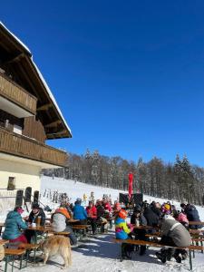 a group of people sitting at tables in the snow at Almberghütte in Philippsreut