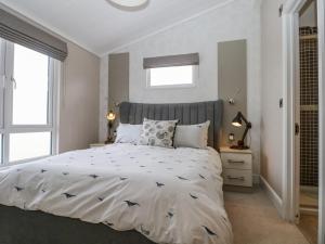 a bedroom with a large bed and two windows at Amberwood 42 in Lymington