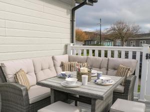 a patio with a table and chairs on a porch at Amberwood 42 in Lymington