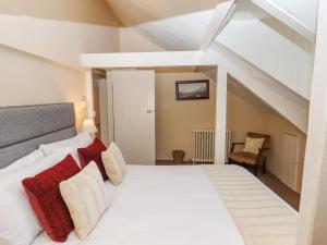 a bedroom with a white bed with red and white pillows at Early Mist Cottage in Newton Abbot