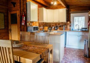 een keuken met witte kasten en een tafel in een huisje bij Scalpay Lodge in Duirinish