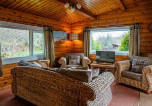 een woonkamer met banken, een tv en ramen bij Scalpay Lodge in Duirinish