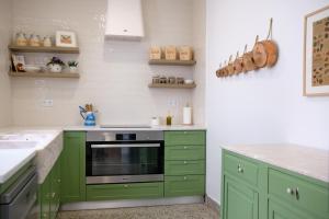 a kitchen with green cabinets and a stove at Ti Noémia - casa de vila in Minde