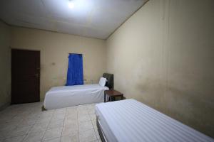 Zimmer mit 2 Betten und einem blauen Vorhang in der Unterkunft SPOT ON 92390 Wilma Kost Syariah in Banjarmasin