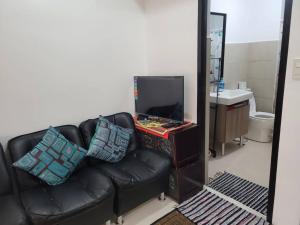 sala de estar con sofá de cuero negro y TV en Mines View - nice studio good for 2-8 persons! en Baguio