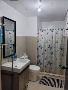 a bathroom with a toilet and a shower curtain at Mines View - nice studio good for 2-8 persons! in Baguio