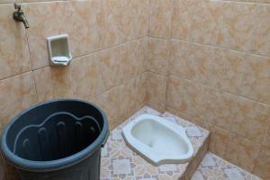 a bathroom with a trash can and a toilet at SPOT ON 92390 Wilma Kost Syariah in Banjarmasin