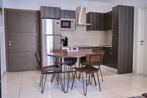 a kitchen with a table and chairs and a refrigerator at King Size Bed & 129 Mb Data Speed 1BR en suite with pool at Embassy Gardens, Cantonment, Accra in Accra