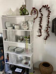 un estante blanco con platos y platos. en Les Magnolias, en Montbrun-les-Bains