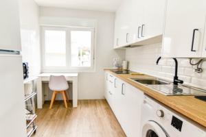 een keuken met witte kasten, een wastafel en een stoel bij Casa en Playa de la Concha in Suances