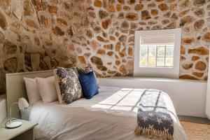 a bed in a room with a stone wall at Trout Escape Farm in Dullstroom