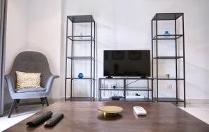 a living room with a tv and a table and a chair at King Size Bed & 129 Mb Data Speed 1BR en suite with pool at Embassy Gardens, Cantonment, Accra in Accra