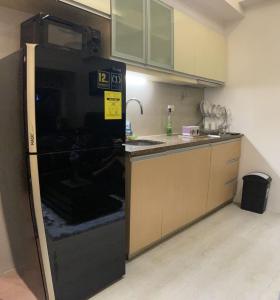 La cuisine est équipée d'un réfrigérateur noir et d'un évier. dans l'établissement EJ's Staycation 22nd F with 200mbps Wi-Fi and NETFLIX, à Manille