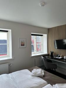 a bedroom with a bed and a desk with a computer at VISIONHOUSE Hotel in Frederikssund