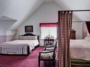 a attic bedroom with two beds and a chair at Aldrich House Bed & Breakfast in Williamsburg +14 photos