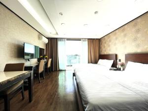 una camera d'albergo con 2 letti e una scrivania di Cordelia Resort a Seogwipo