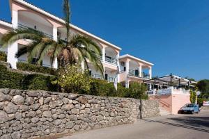 a house with a stone wall and a palm tree at Nissaki Sea View Apartments in Nisakion
