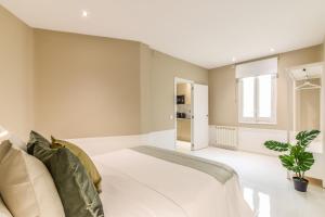 Un dormitorio con una gran cama blanca y una ventana en AP Embajadores X, en Madrid